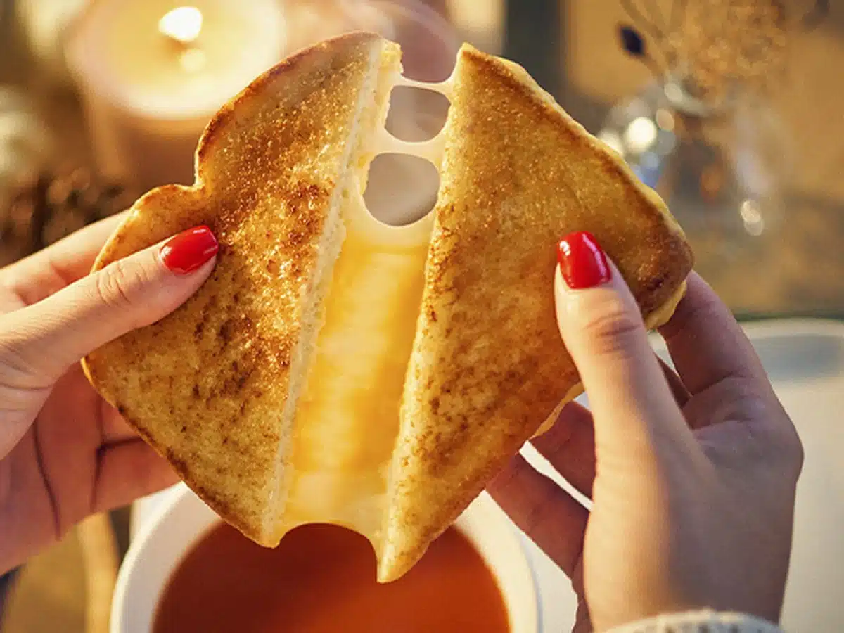 Grilled cheese sandwich over a bowl of tomato soup for a best canned tomato soup for grilled cheese buying guide