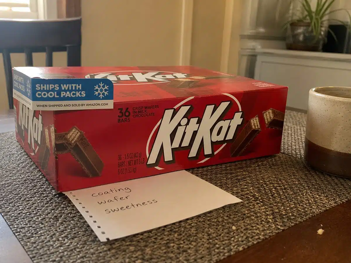 KIT KAT milk chocolate 36-bar case beside a flavor comparison note on a kitchen table